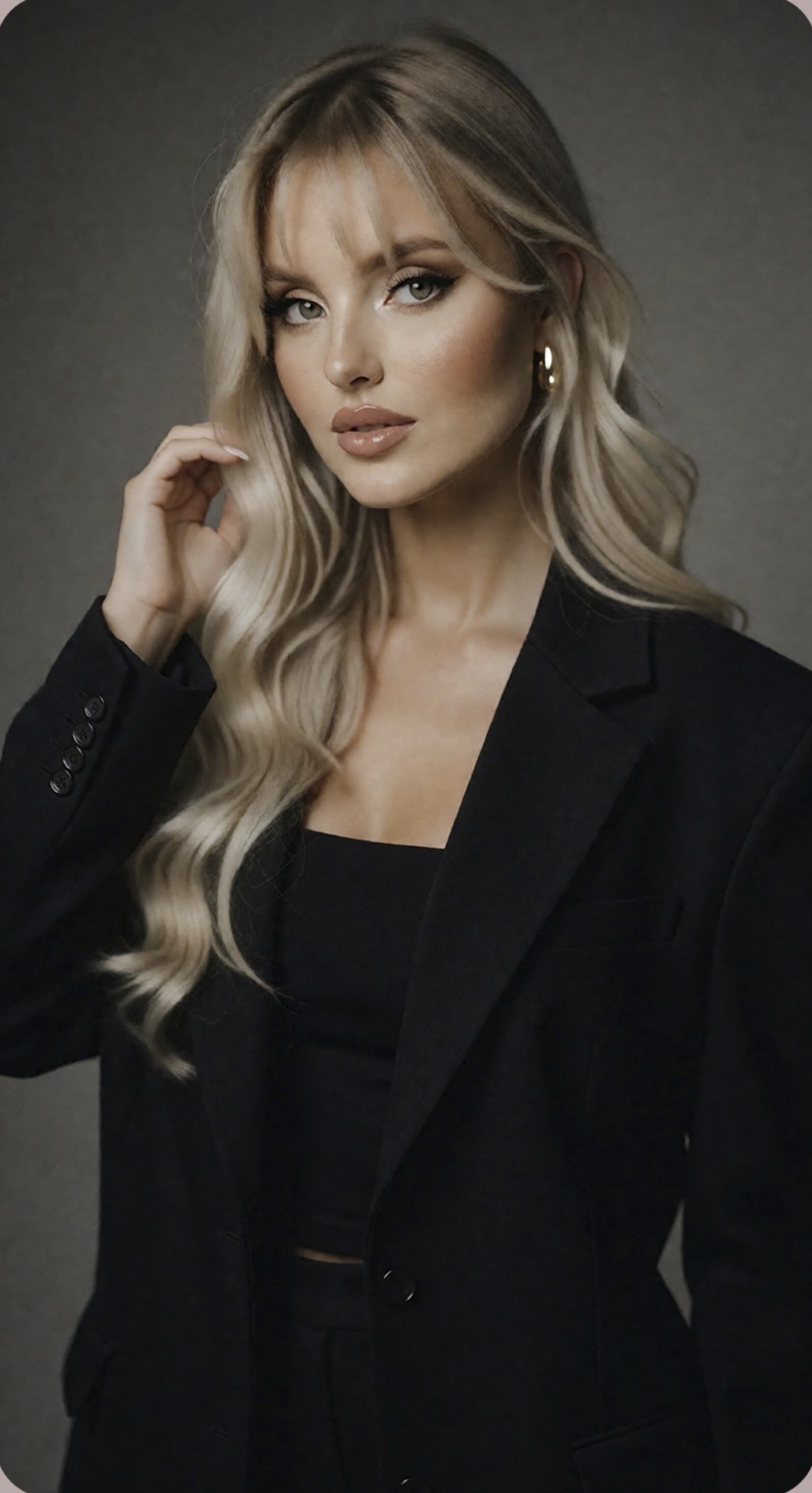 Allison Hernandez in a black blazer, one hand in her hair.